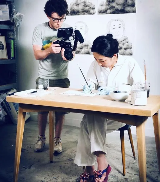 Vidéaste filmant une artiste au travail dans son atelier